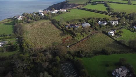 toma aérea de seguimiento de drones de un land rover 4x4 que viaja a través de un pueblo inglés en el campo con una costa rocosa - lee bay, playa, ilfracombe, devon, inglaterra