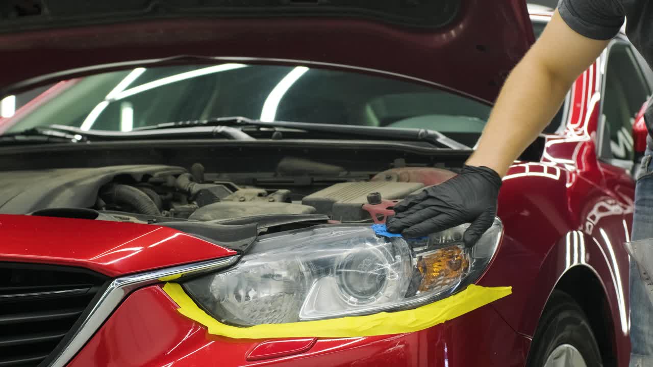 pulido de faros, procesamiento de luces de automóviles. un trabajador de servicio de automóviles pulida el faros de un automóvil de pasajeros. pulido profesional.