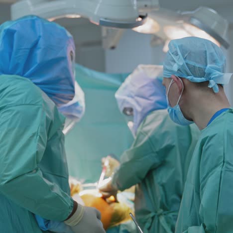 operating theatre during pandemic. professional doctors wearing protective blue suits conduct a surgery to a sick patient in clinic. covid-19