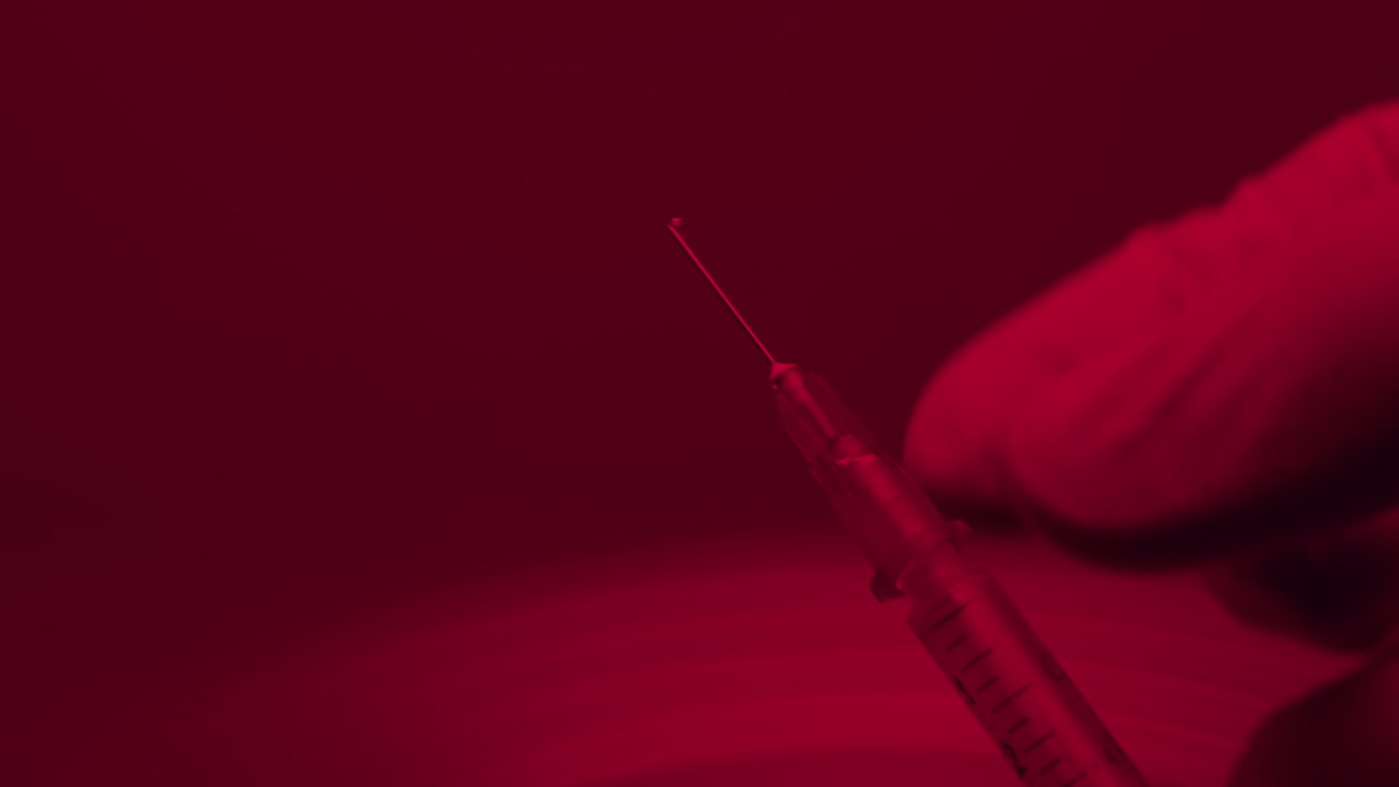 Close-up of a syringe and hand