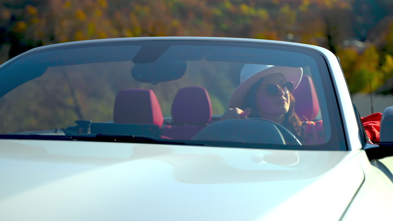 Donna che guida un'auto decappottabile bianca su una strada panoramica