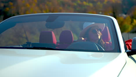 woman driving a white convertible car on a scenic road