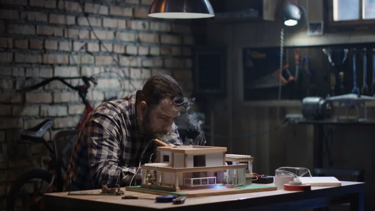 Man Working on Miniature House Model in a Workshop