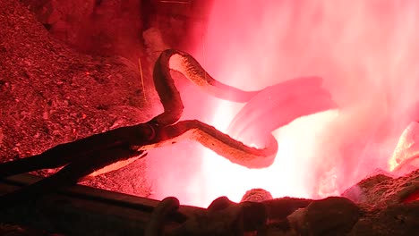 blacksmith tongs moving and heating metal bowls through hot flames in ancient traditional oven