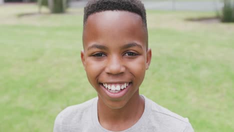 Video-portrait-of-smiling-african-american-schoolboy-in-school-playing-field,-with-copy-space