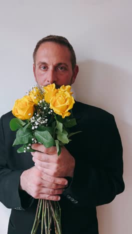 hombre con rosas amarillas en un traje negro