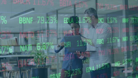 Animation-of-trading-board-over-diverse-coworkers-standing-with-laptop-and-discussing-reports