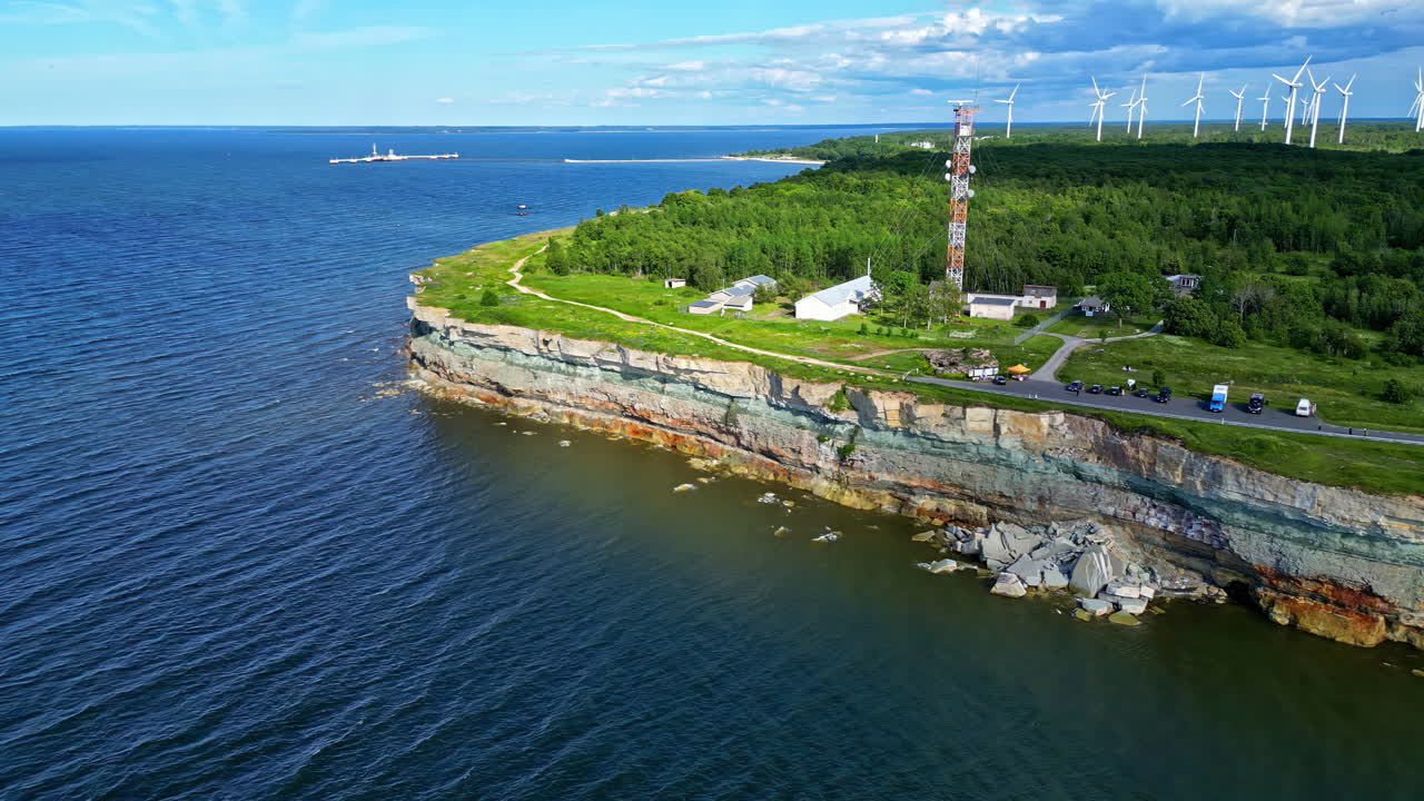 Aerial view of a sea coast with wind turbines in the background on a sunny day