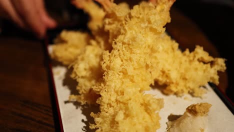 hands arranging tempura on a serving plate