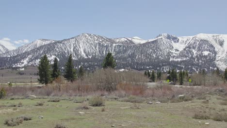 imágenes de drones de 4k rotación lenta de un prado de principios de primavera en lagos gigantescos con montañas gigantescas y picos nevados en la distancia