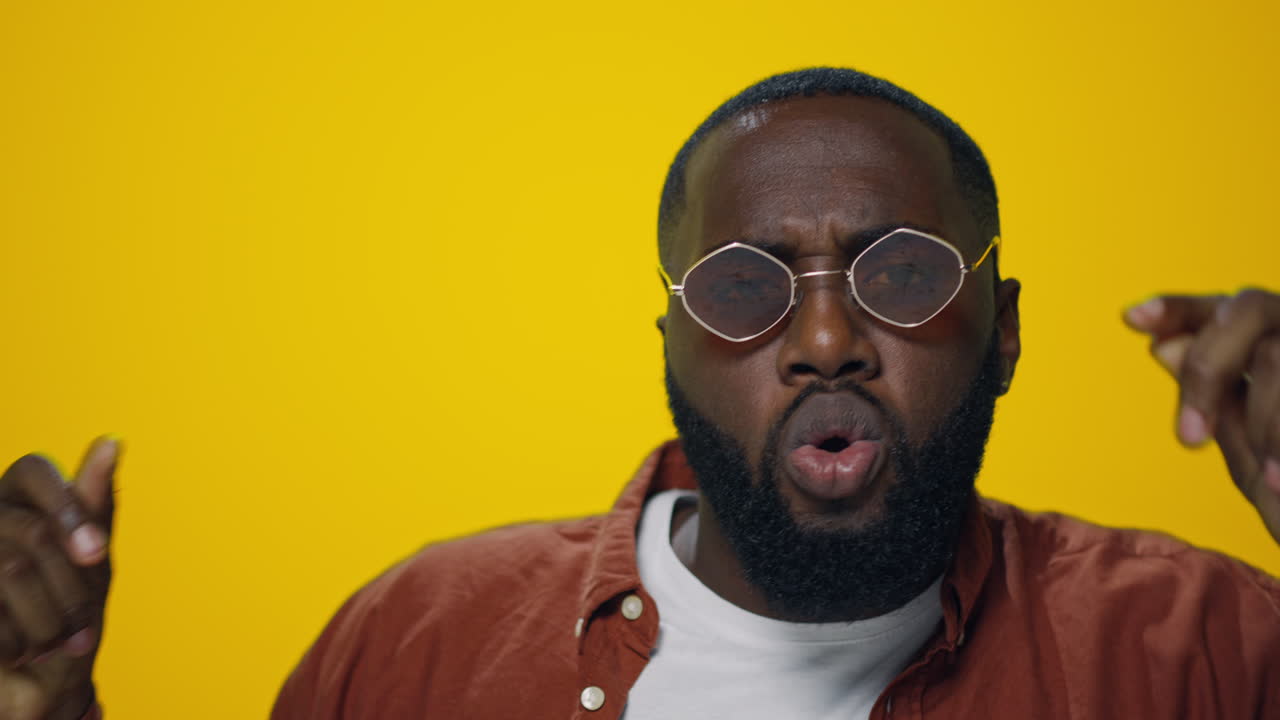 Ritratto di uomo afroamericano che balla su sfondo giallo. Uomo che si diverte