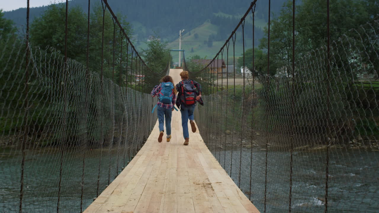 la pareja corre el puente de las montañas en el río de la naturaleza. los viajeros emocionados se divierten afuera.