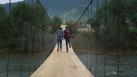 couple run mountains bridge on nature river. excited travelers have fun outside.