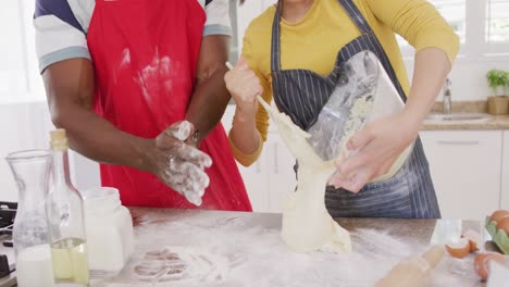 Happy-diverse-couple-wearing-aprons-and-baking-in-kitchen