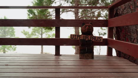 estatua de un oso con un letrero que dice "límpiate las patas" en un frío día de invierno