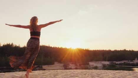 mujer joven con un hermoso vestido ligero corre a lo largo de la playa hacia la puesta de sol estirando los brazos hacia t