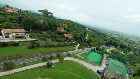 drone flying over quaint medieval town houses and nature surroundings in lucignano, tuscany italy