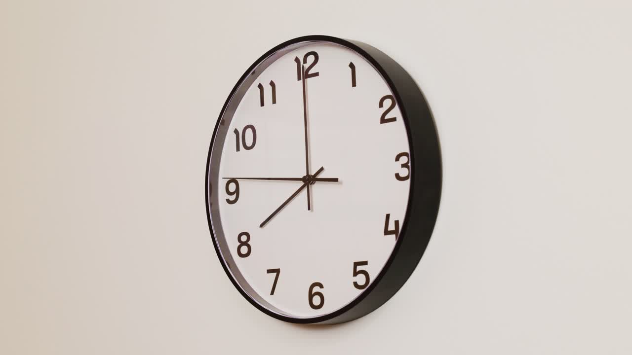 A close-up 4K shot of a black and white wall clock filling the frame, showing the time as 8:00.