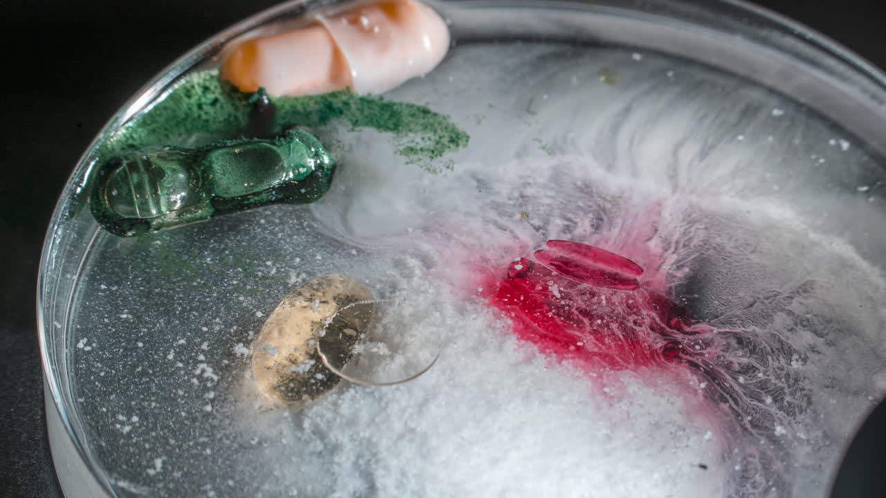 Pill dissolving in liquid, timelapse showing colorful swirls and foam