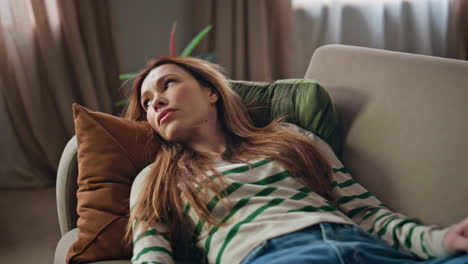 tired woman lying sofa at domestic weekend closeup. serious girl relaxing home
