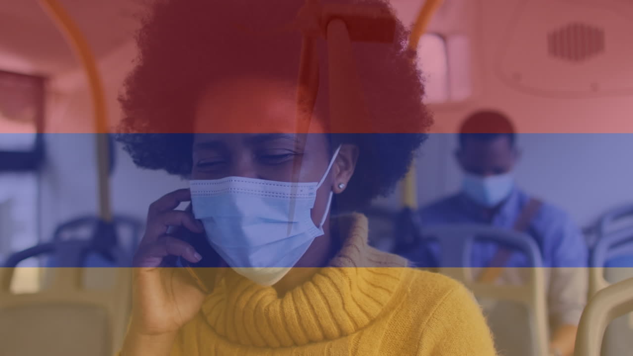 animación de la bandera de colombia sobre mujer afroamericana con máscara facial usando teléfono inteligente en el autobús