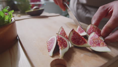 person cutting figs on a wooden cutting board