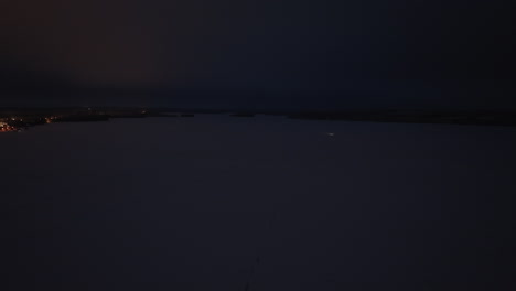 aerial view of a snowmobile driving on a snowy lake, winter night in finland