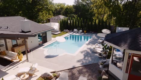 a push in aerial drone shot of the backyard of a luxury home with a nice pool and outdoor swimming area
