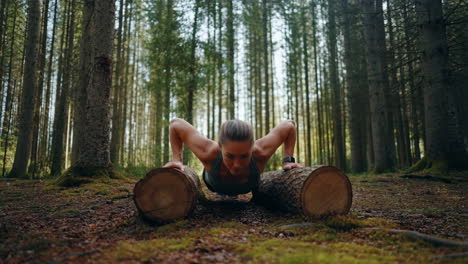 woman doing push-ups on logs in a forest