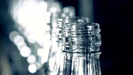 close up of opened necks of moving empty glassy bottles