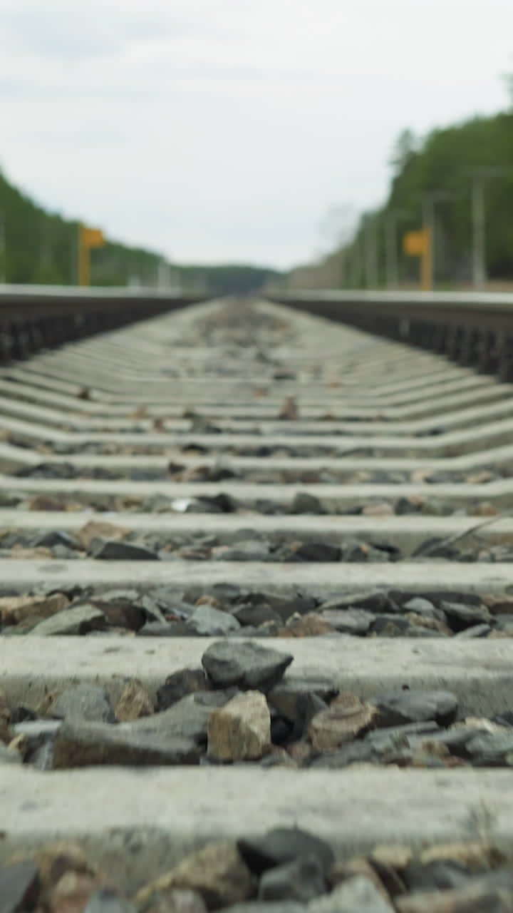 Close-up slow view of a railway track focusing on the concrete sleepers and gravel ballast, with perspective leading towards the horizon