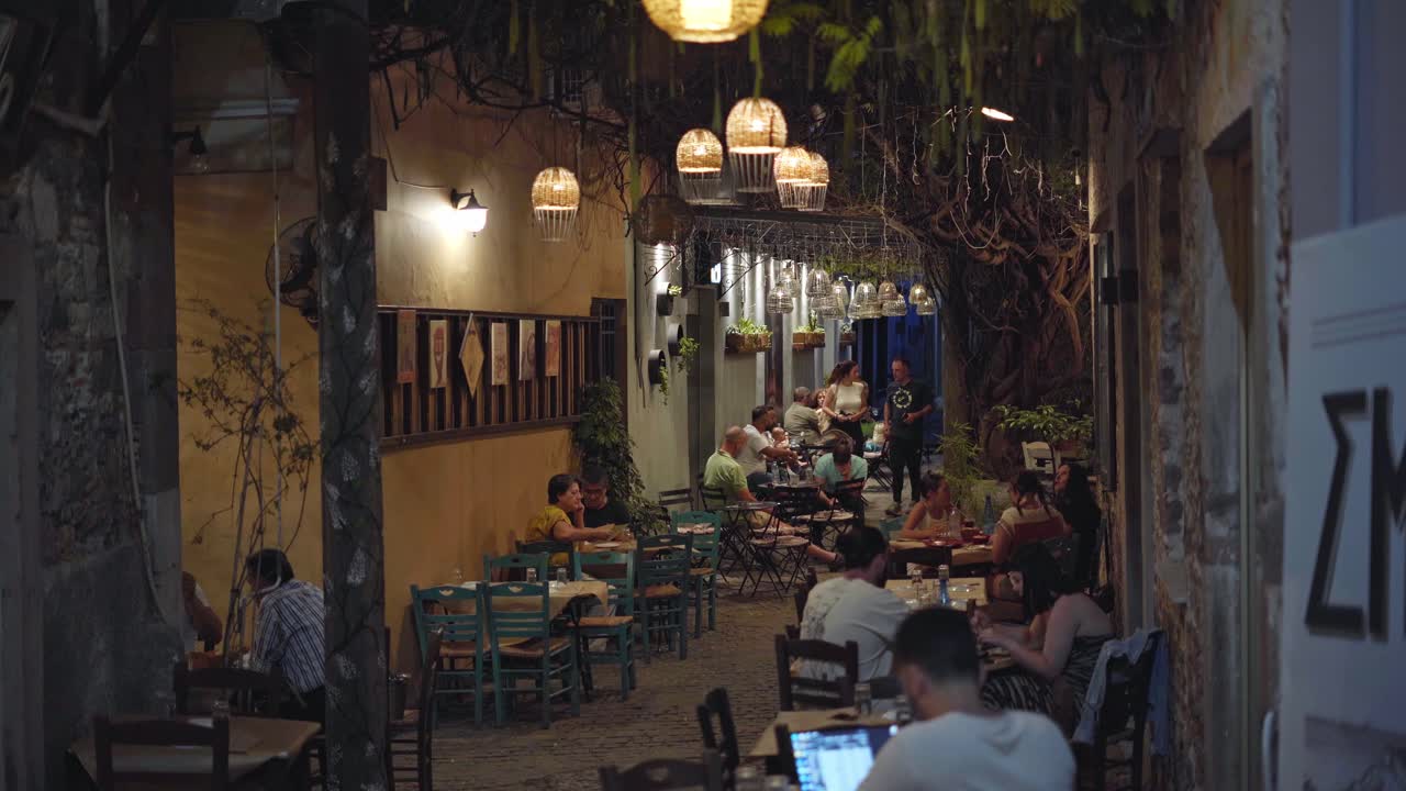 Bustling outdoor cafe scene in Mytilene, Greek island of Lesbos at night, Handheld gimbal shot
