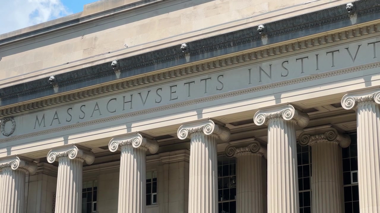 Primo piano della facciata dell'Edificio 10 del MIT, centrato sull'iscrizione intagliata “Massachusetts Institute of Technology” sopra le colonne ioniche. Le colonne e l'iscrizione sono la facciata classica del Macla.
