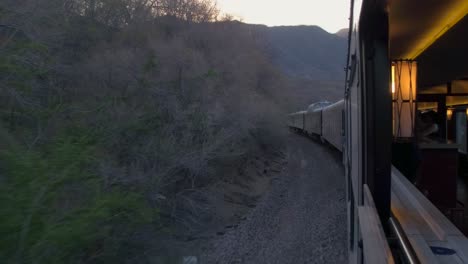 the view from the window in a moving train through arid scenery at sunset