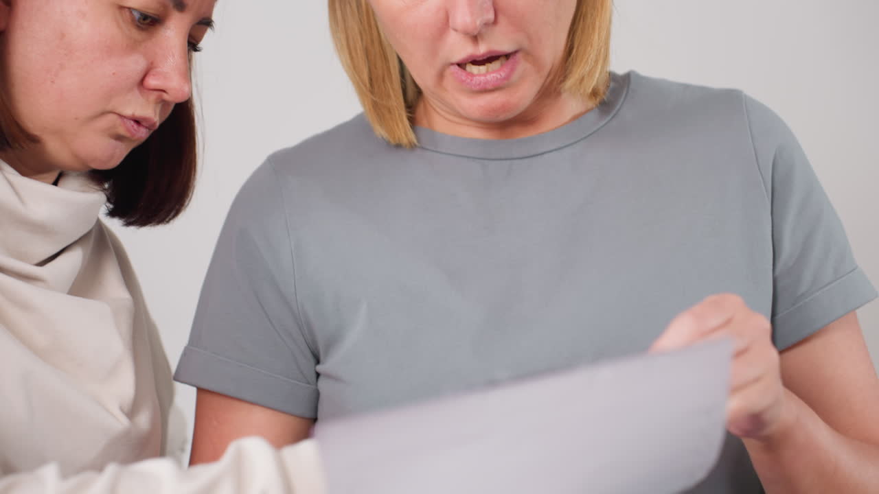 Elegant ladies reviewing design pattern paper closely during collaborative discussion, carefully examining options for selection, sharing ideas and focusing on project planning with teamwork
