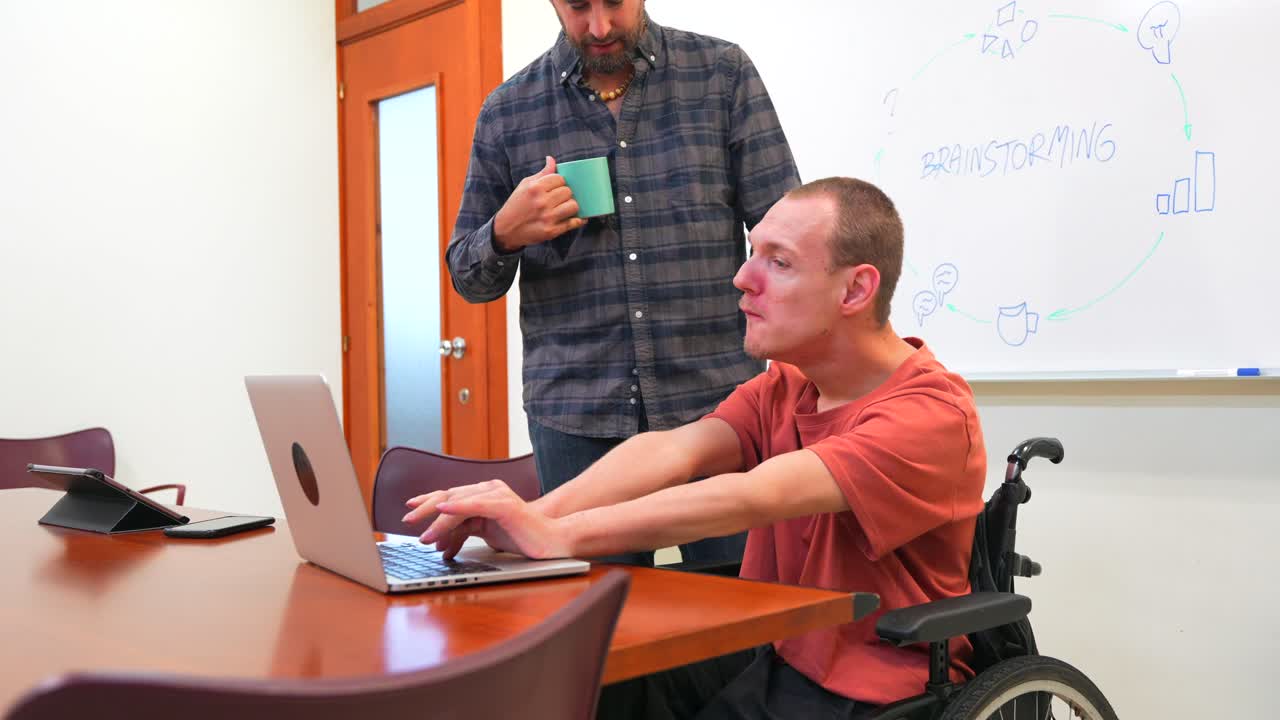 Inclusive Meeting with Wheelchair User Working on Laptop
