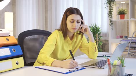 Young-businesswoman-working-from-home-at-computer-doing-her-online-work-on-laptop-and-taking-notes.