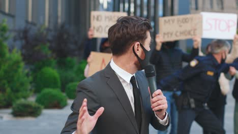 covid 19에 대한 항의에서 인터뷰를 제공하는 보호 마스크를 착용하는 백인 기자 또는 특파원
