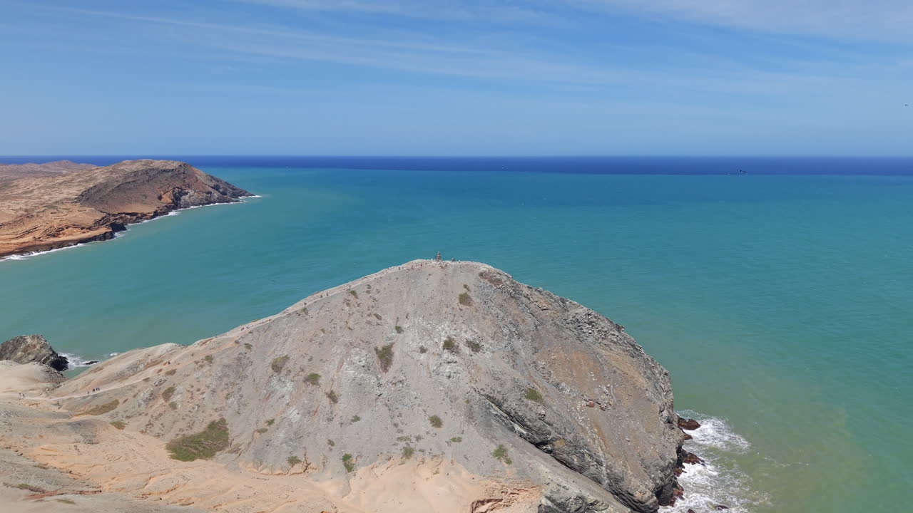 Riprese aeree mozzafiato di Pilon de Azucar, Cabo de la Vela, che mostrano un terreno costiero aspro e acque turchesi sotto un cielo azzurro limpido. Ideale per immagini di viaggio e natura.