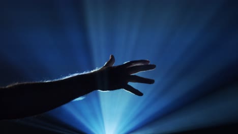 hand reaches out into ghostly light beams