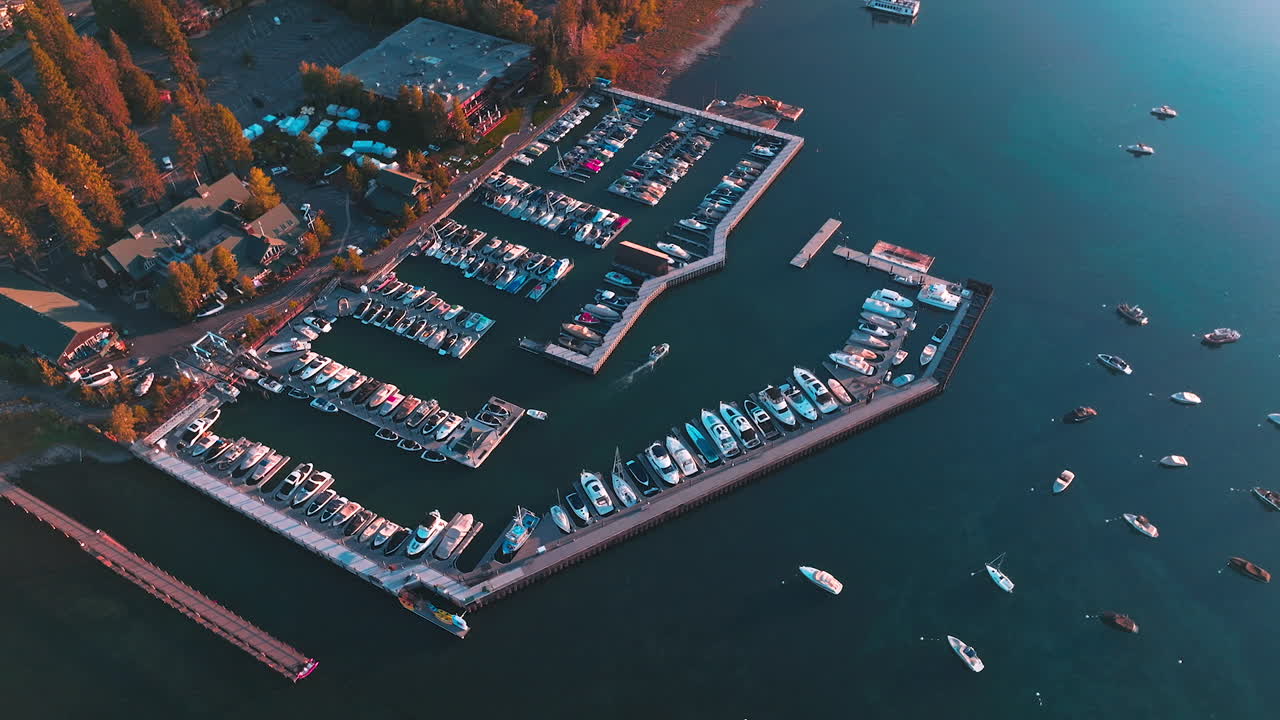 Lots of boats and yachts at the pier of Lake Tahoe. Drone footage over the lake waters with many boats sailing on.