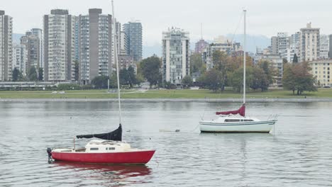 2-Veleros-Bailando-En-El-Agua,-Con-El-Horizonte-De-Vancouver-Detrás