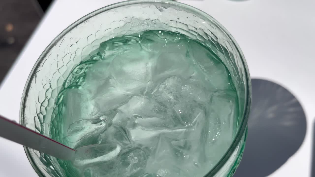 화창한 날 테라스에서 점심을 먹기 위해 앉아 얼음물을 휘저으며