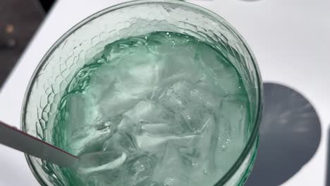 화창한 날 테라스에서 점심을 먹기 위해 앉아 얼음물을 휘저으며