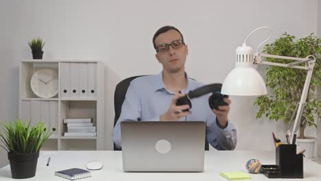 man working on laptop computer and listening to music at desk in home office, slow motion, close up