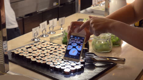 Making-photo-of-sushi-with-mobile-in-cafe