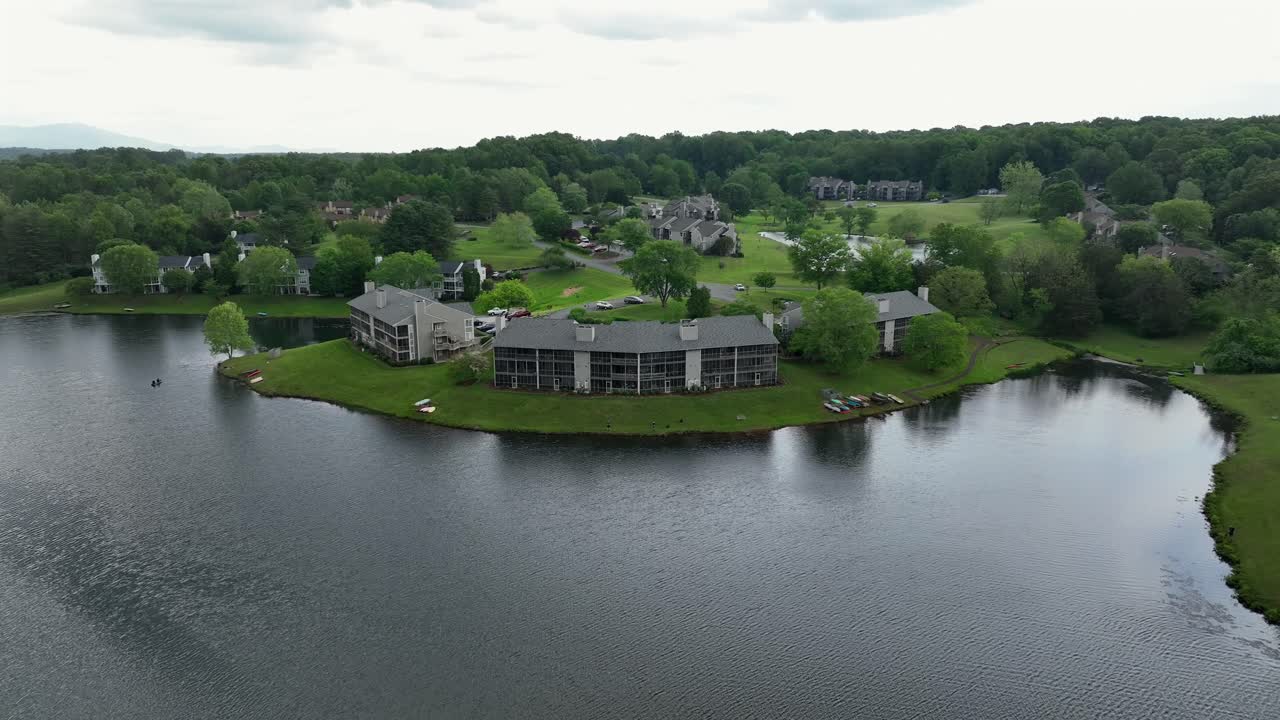 Modern apartment buildings with green trees and private lake in Virginia. Aerial descend wide shot. Scenic and peaceful neighborhood in america.