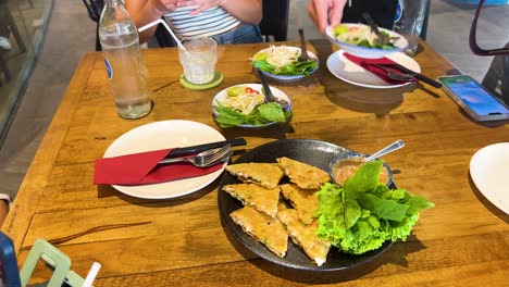 a table set with crispy shrimp pancakes and fresh greens in a well-lit vietnamese restaurant, capturing a casual dining moment