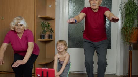 Old-grandmother-grandfather-with-child-girl-kid-doing-workout-exercises,-training,-fitness-at-home