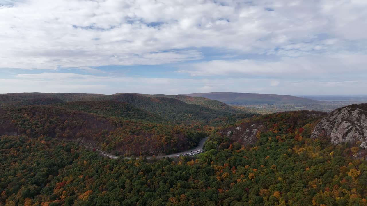 una vista aérea sobre las montañas en el norte del estado de nueva york durante el cambio de follaje de otoño, en un hermoso día con nubes blancas